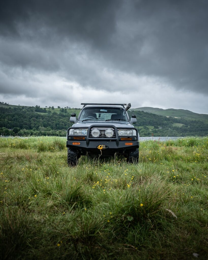 a truck parked in a grassy field under a cloudy sky