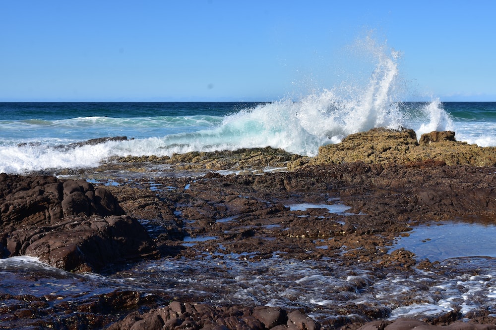 a wave crashes on a rocky shore near the ocean