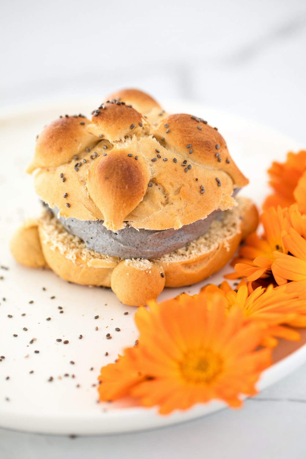 a white plate topped with a sandwich and flowers