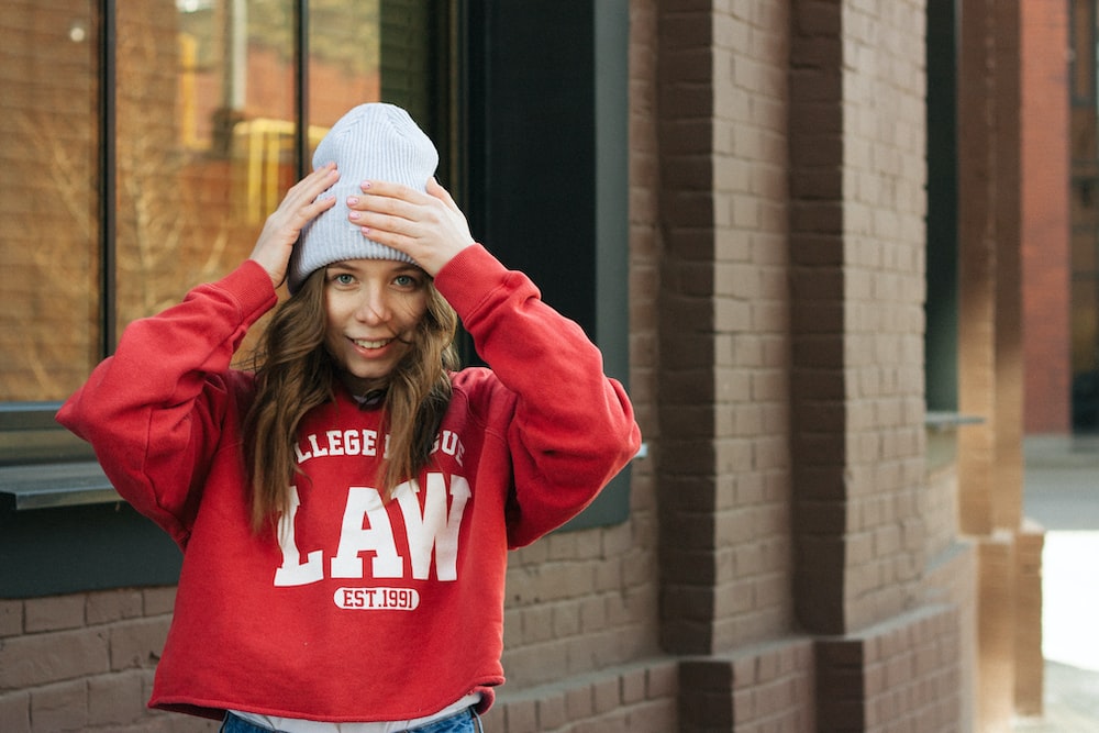 a woman in a red sweatshirt is covering her eyes