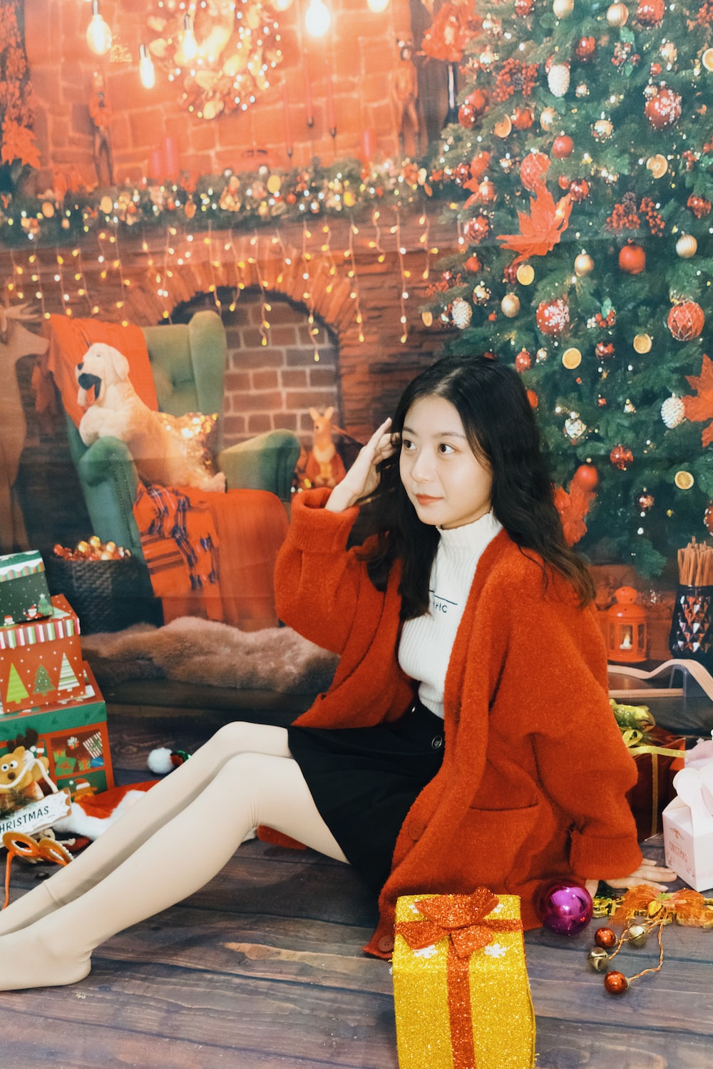 a woman sitting in front of a christmas tree