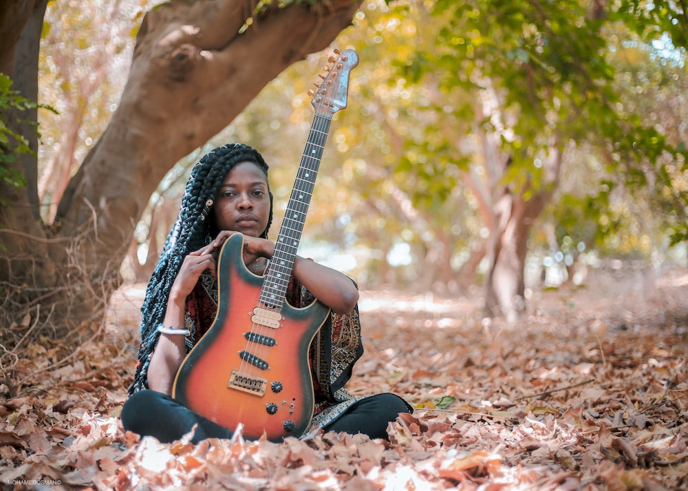 a woman sitting on the ground with a guitar