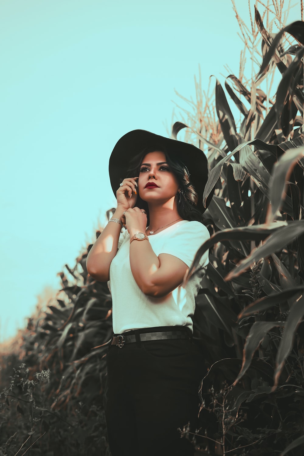 a woman standing in a corn field talking on a cell phone