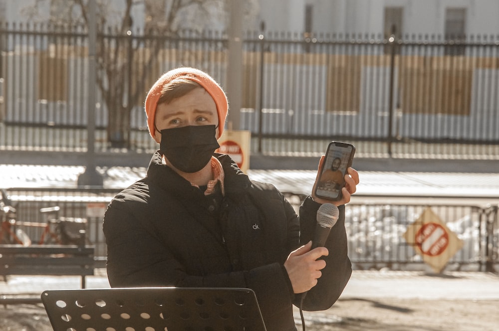 a woman wearing a face mask and holding a cell phone