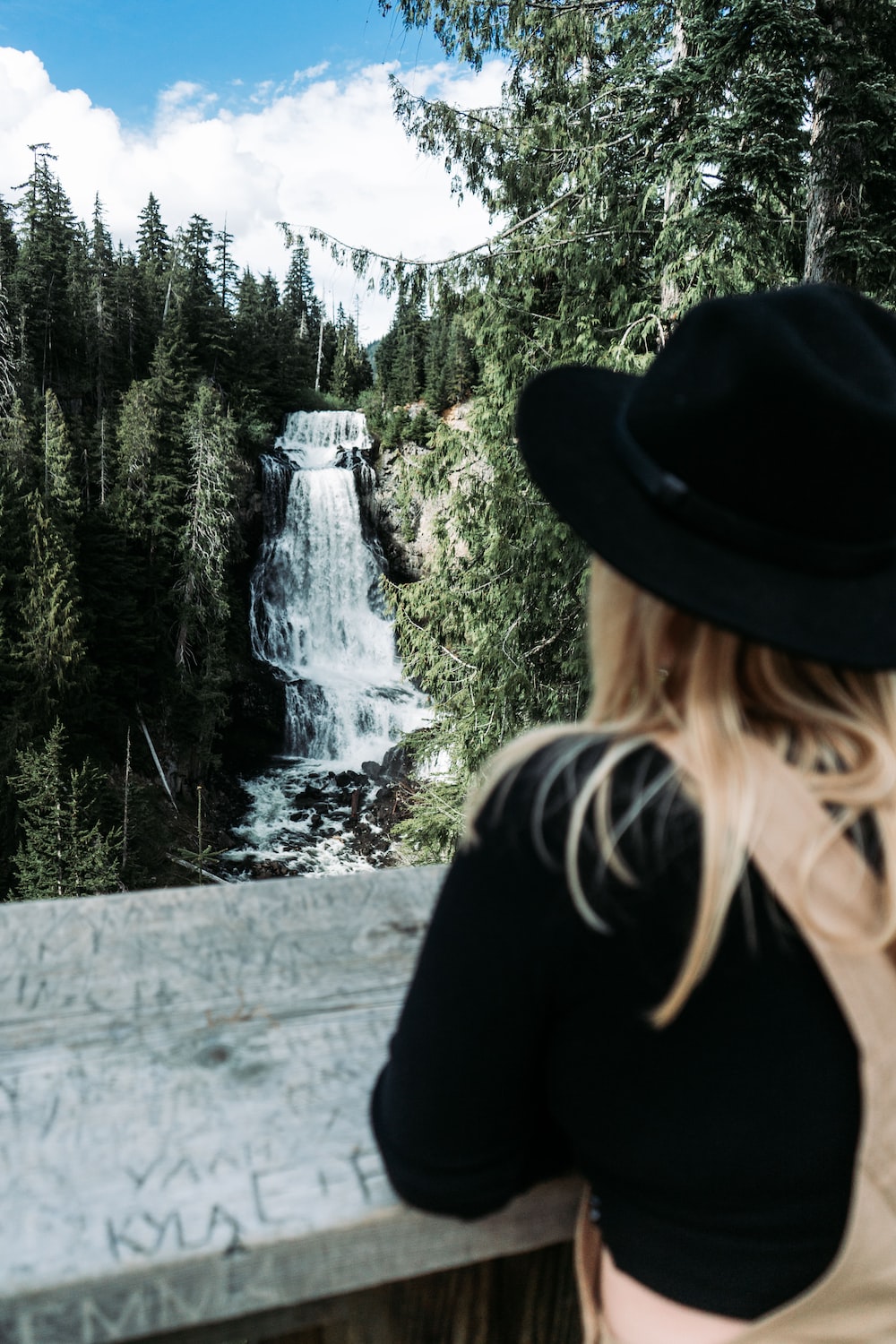 a woman wearing a hat looking at a waterfall