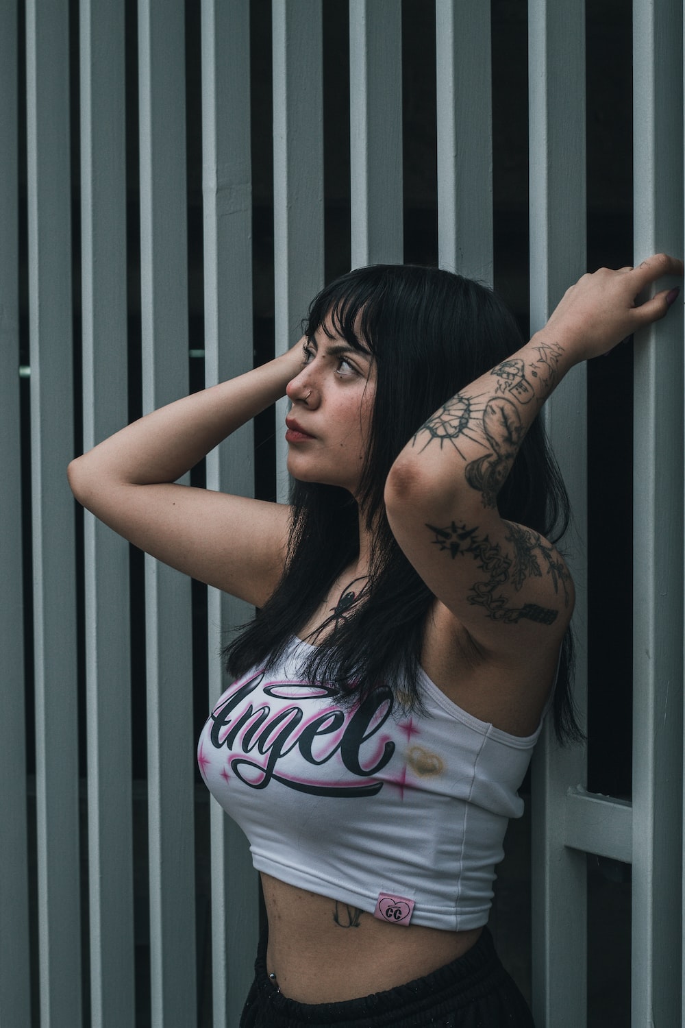 a woman with a tattoo on her arm leaning against a wall