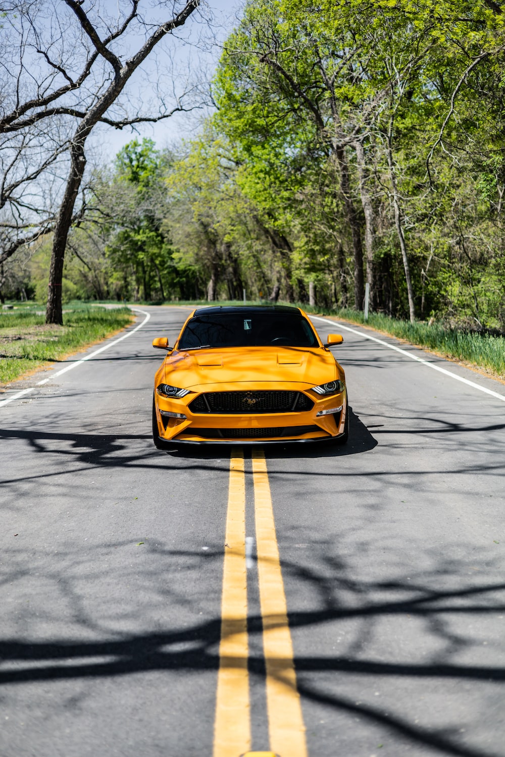 a yellow sports car is driving down the road