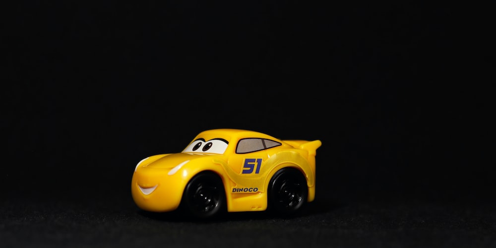 a yellow toy car sitting on top of a black surface