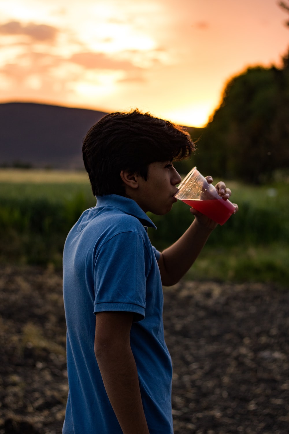 a young man drinking from a plastic cup