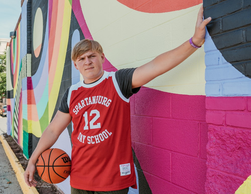 boy in red and white crew neck t-shirt holding basketball