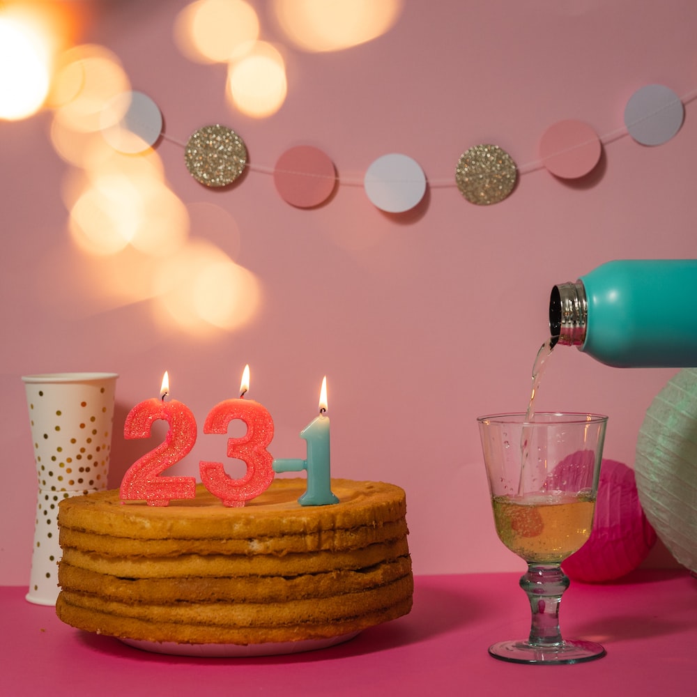 brown cake with candles on pink table