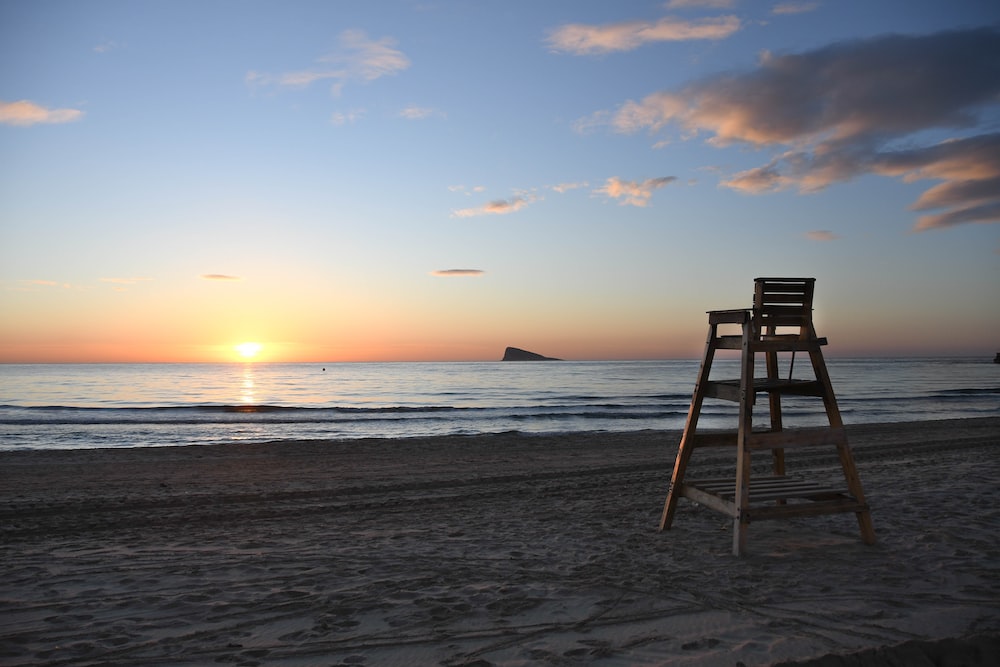 brown wooden chair on beach during sunset