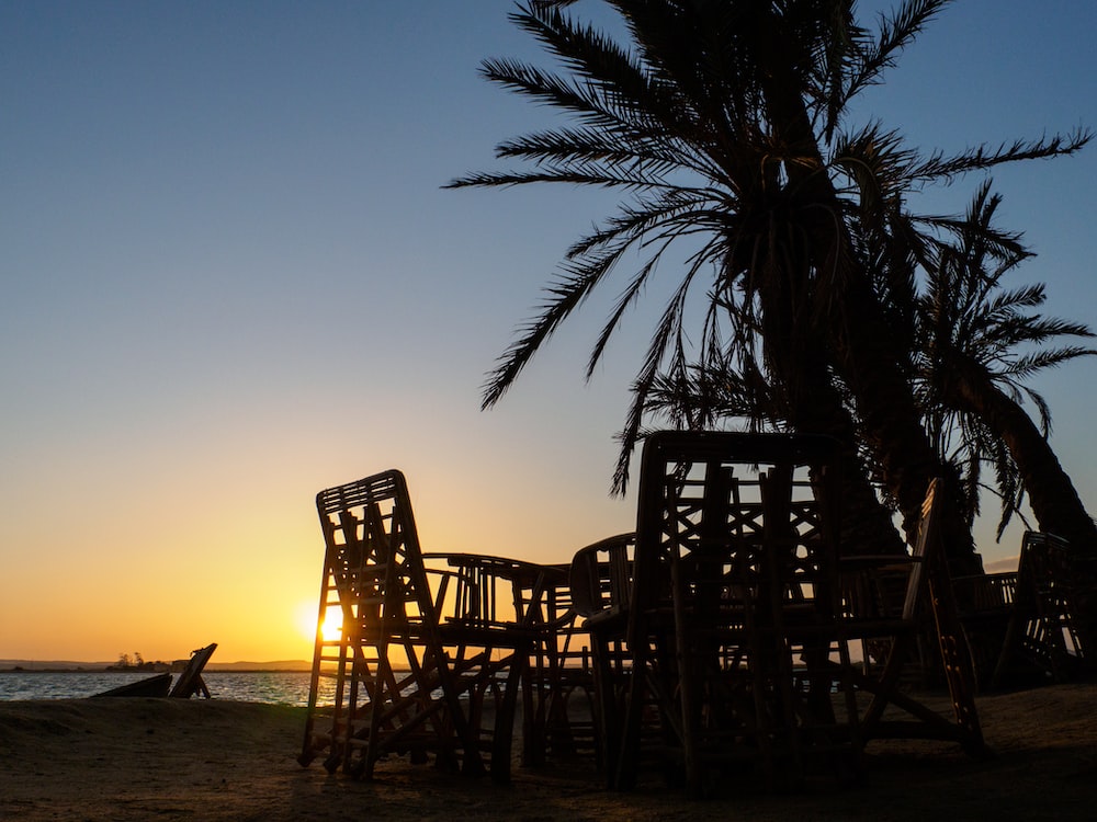 brown wooden chairs on beach during sunset