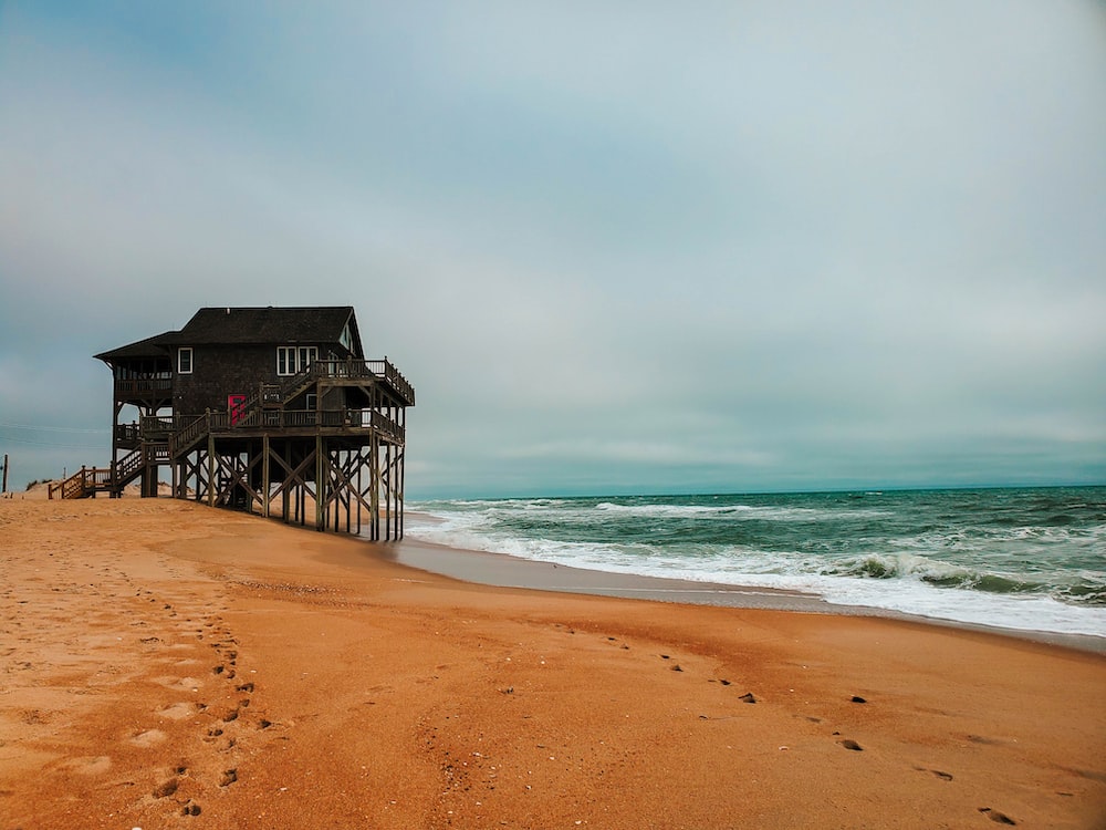 brown wooden house on beach shore during daytime