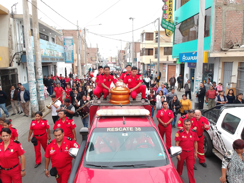 coffin on red truck beside men in red uniform
