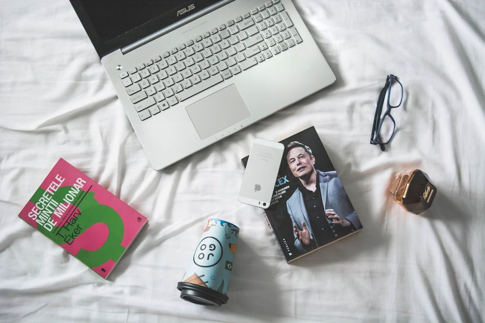 flat lay photography of MacBook and book with eyeglasses