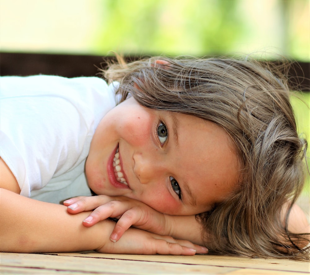 girl in white t-shirt lying on brown wooden bench