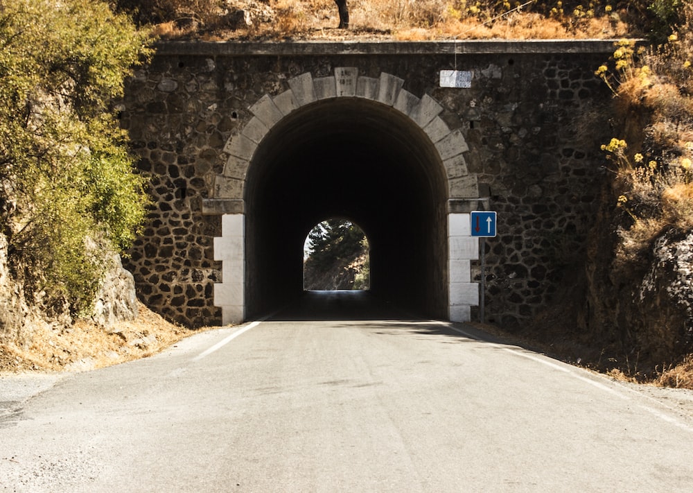 gray concrete tunnel with arch shaped hole