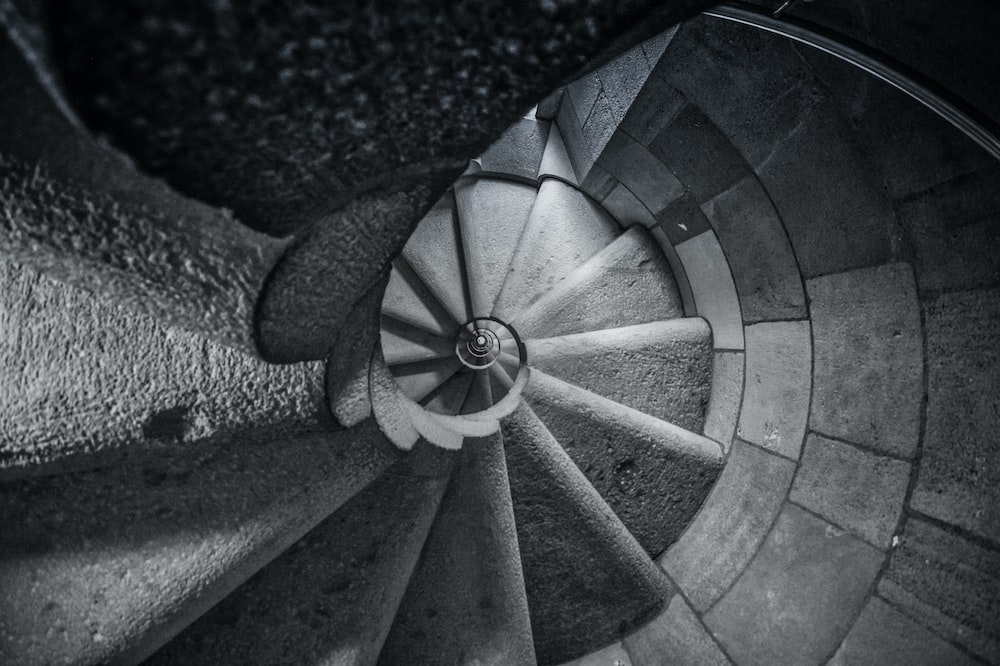 grayscale photo of concrete spiral stairs