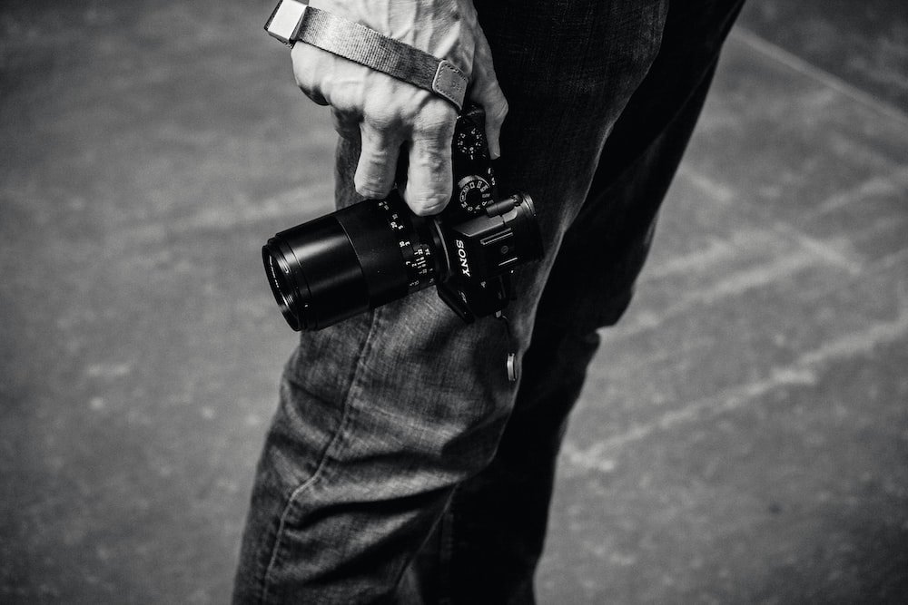 grayscale photo of person holding DSLR camera