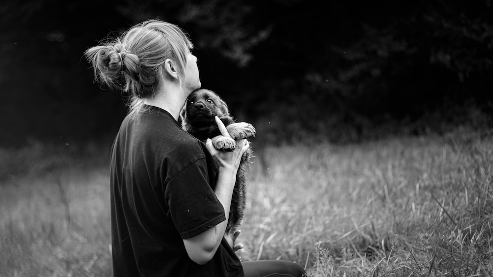 grayscale photo of person holding puppy