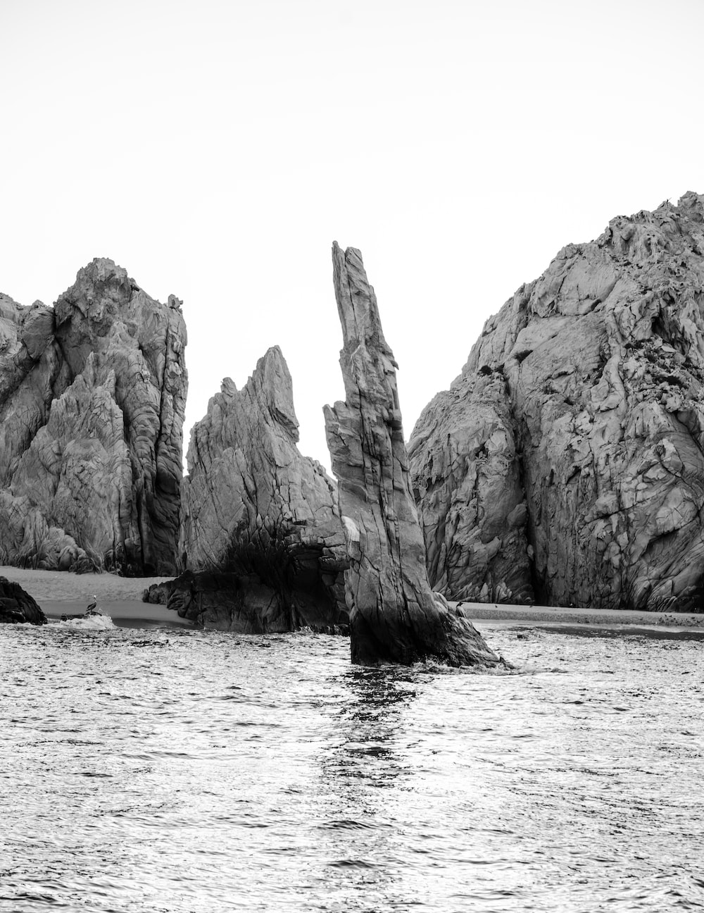 grayscale photo of rock formation on sea