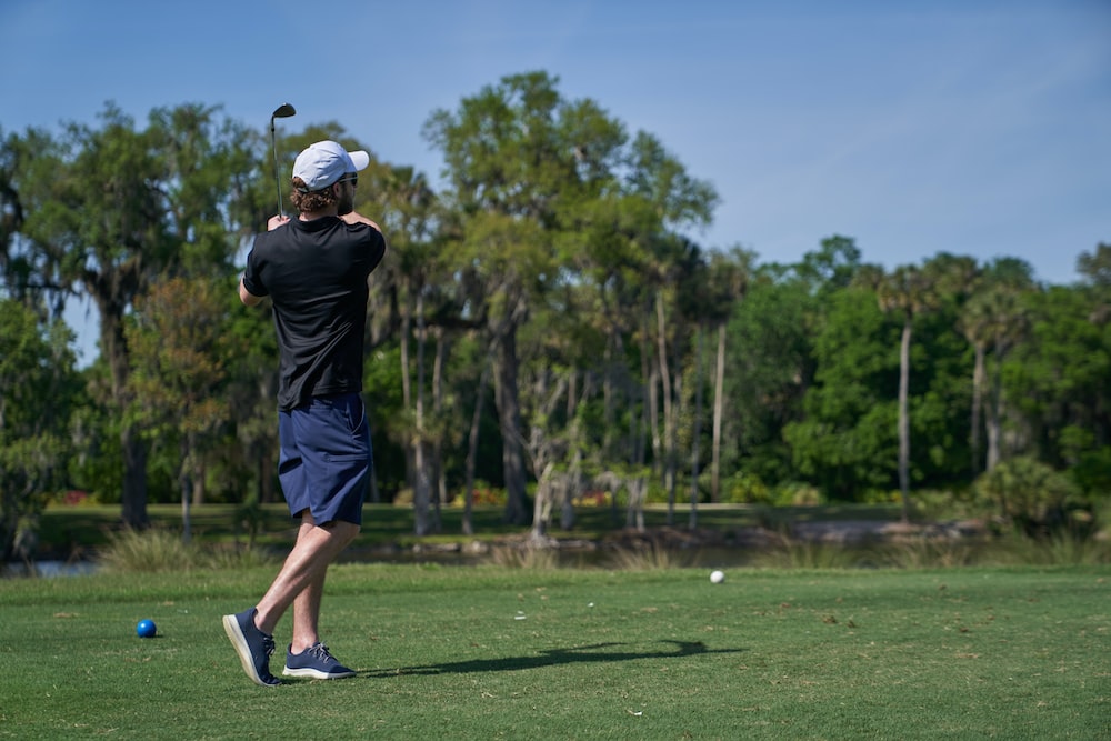 man in black shirt and shorts playing golf during daytime