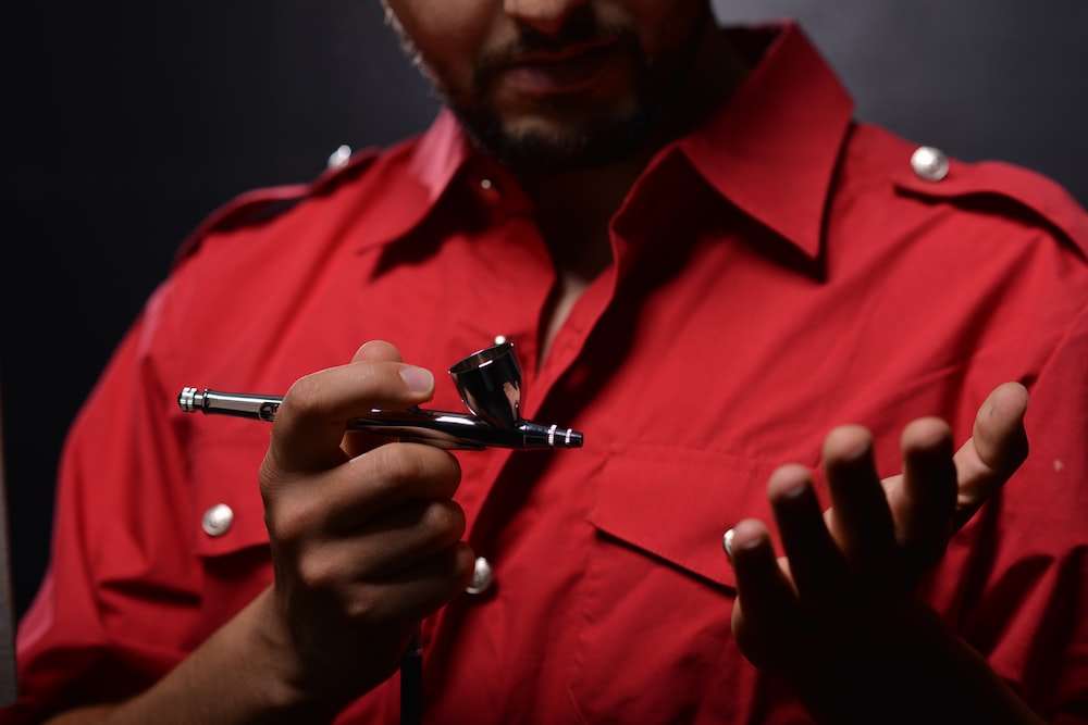 man in red button up shirt holding black pen