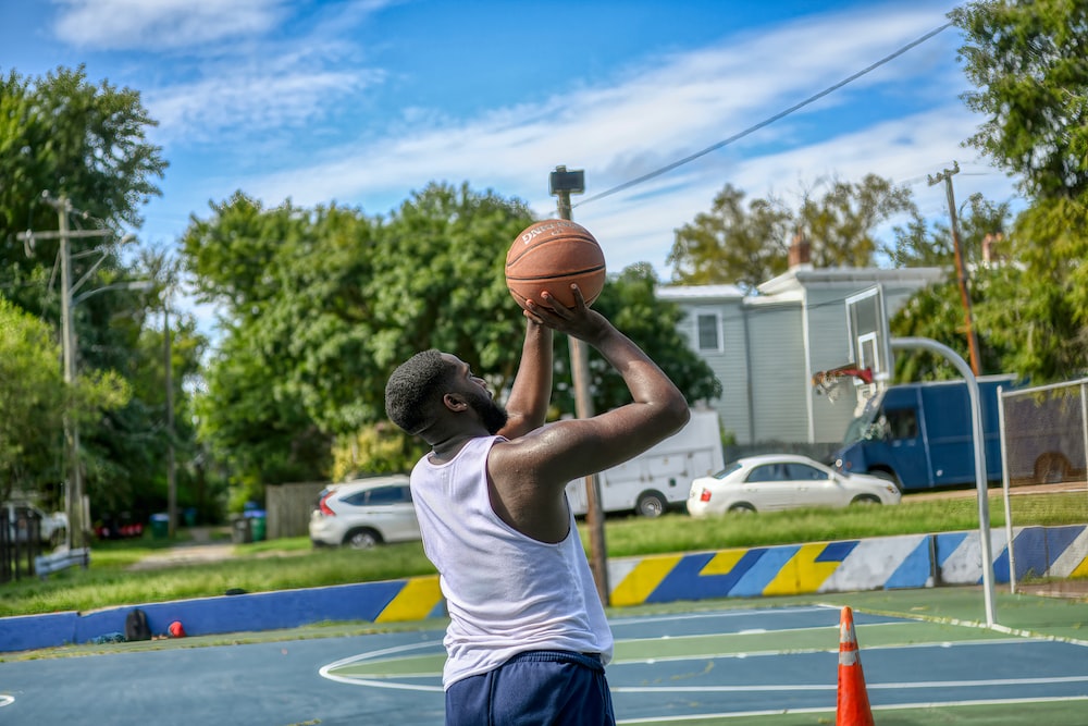man in white tank top holding basketball