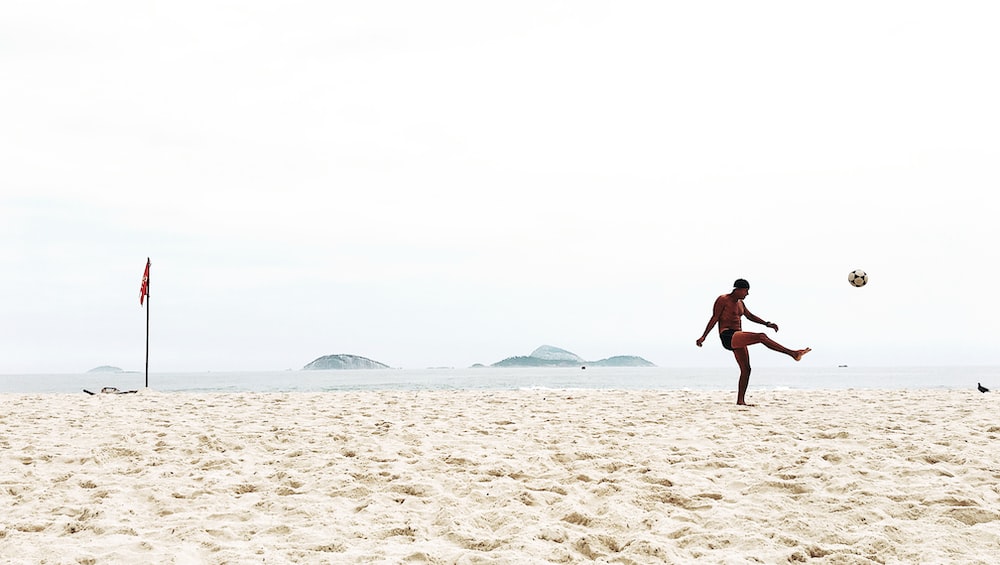 man playing soccer on beach