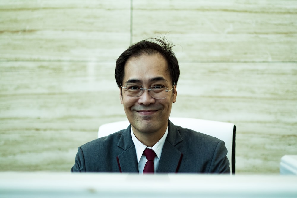 man wearing formal suit sitting and smiling