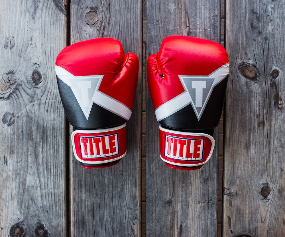 pair of red-and-black Title training gloves on grey wooden plank