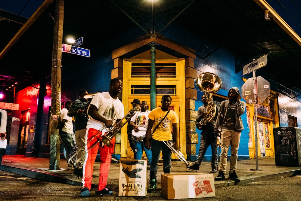 people holding musical instruments while standing on street during nighttime