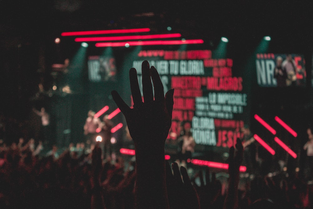 people raising their hands in front of stage