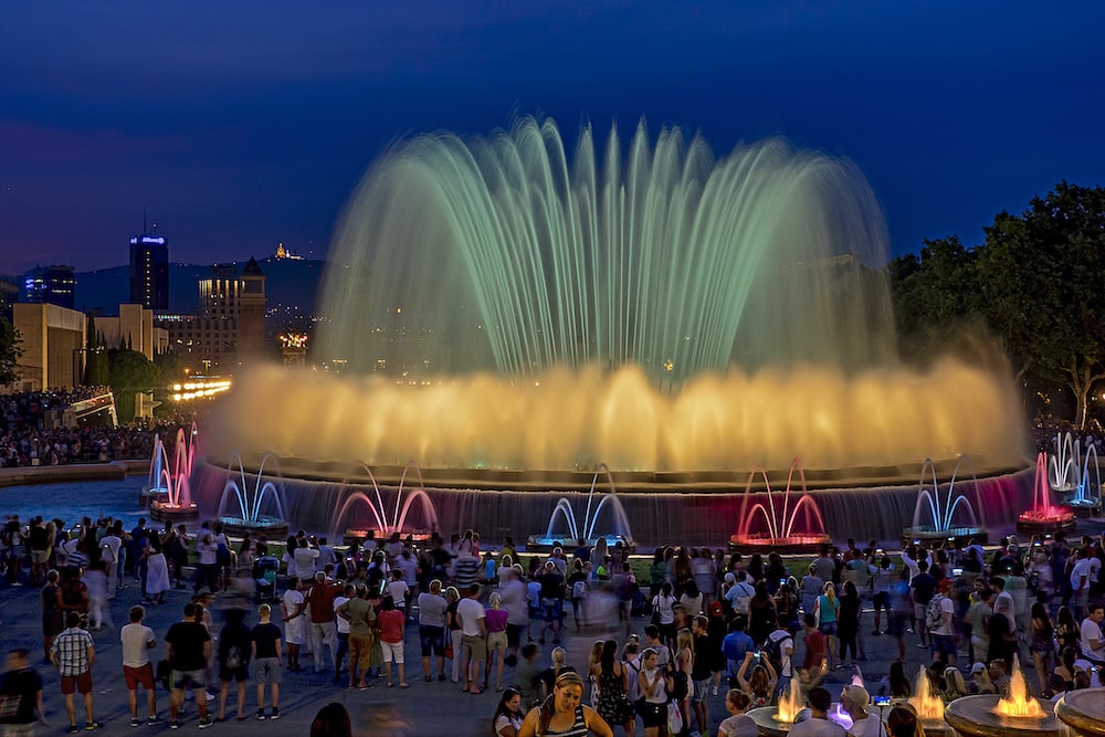 people standing near fountain during night time