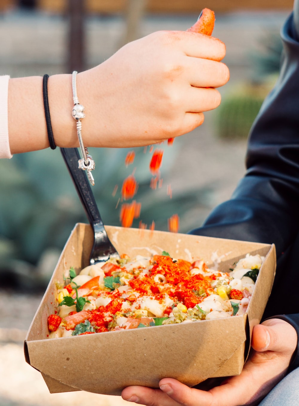 person holding brown box with vegetable salad