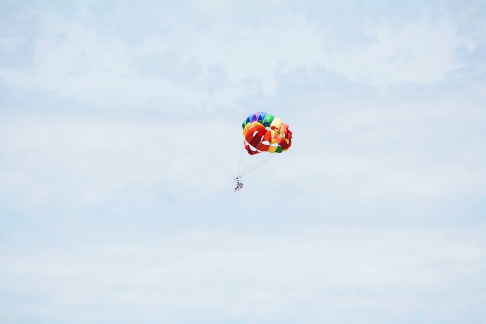 person on parachute sky diving under cumulus clouds