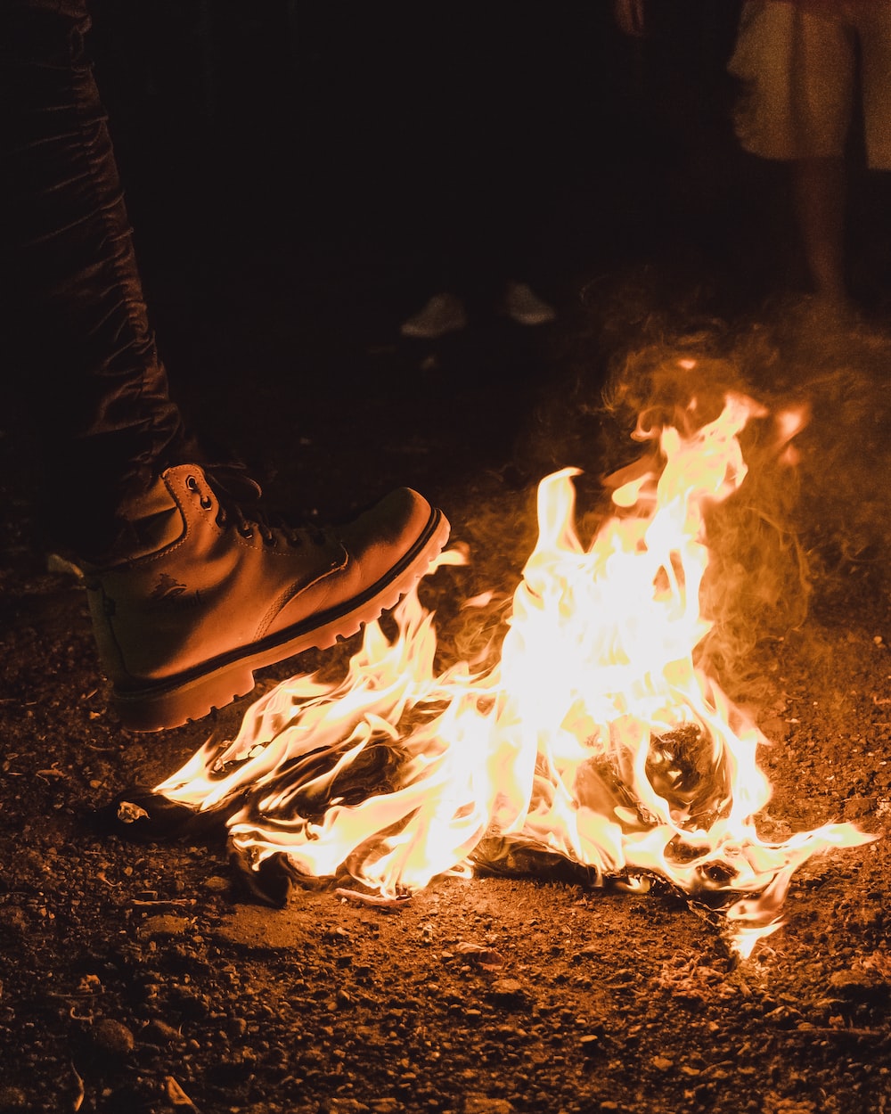 person wearing black leather shoes in front of bonfire