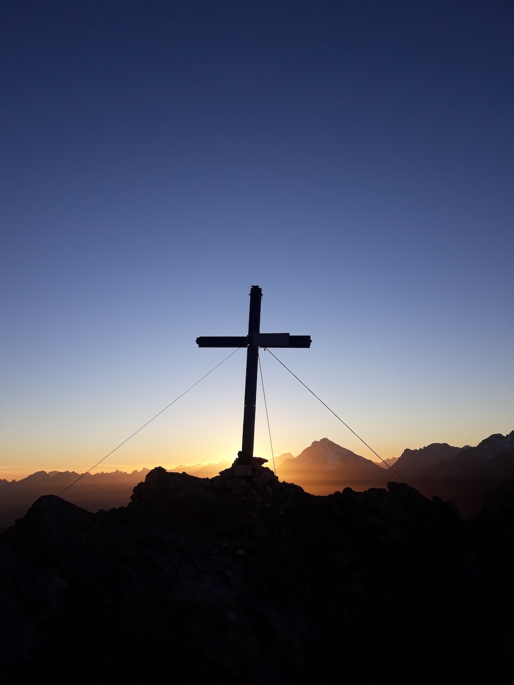 silhouette of cross on rock formation during sunset