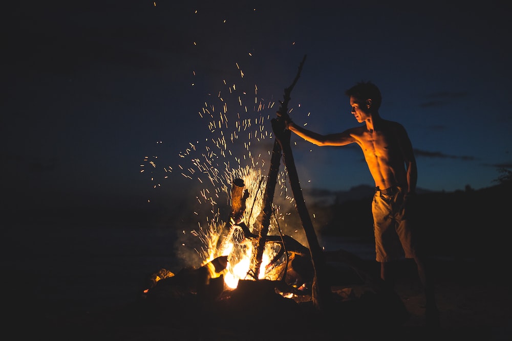 topless man lighting bonfire