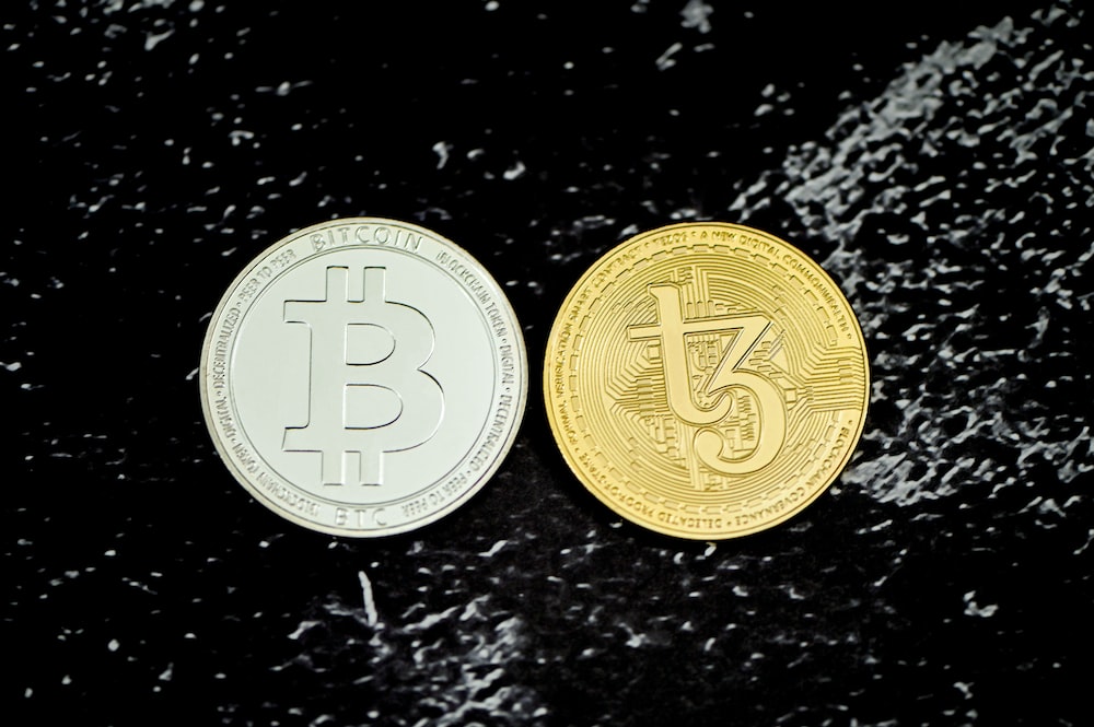 two bitcoins sitting side by side on a black surface