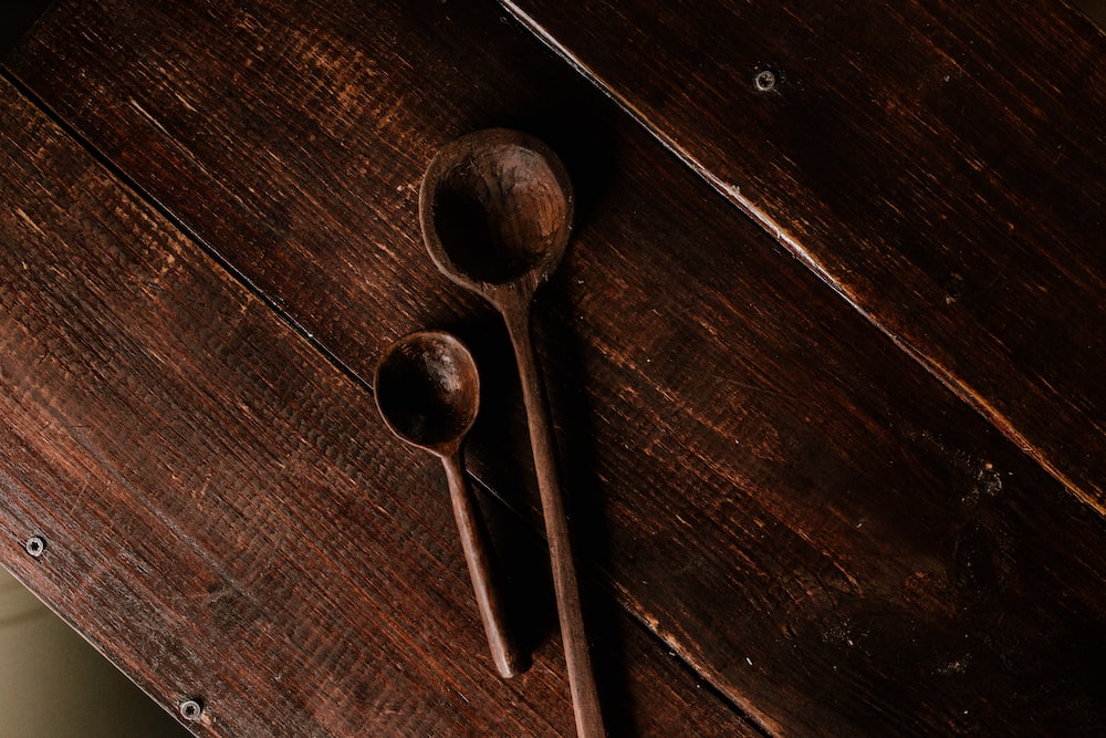 two brown wooden spoons on brown wooden table