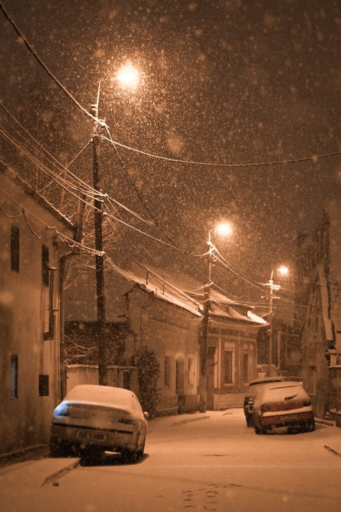 two cars parked on a snowy street at night