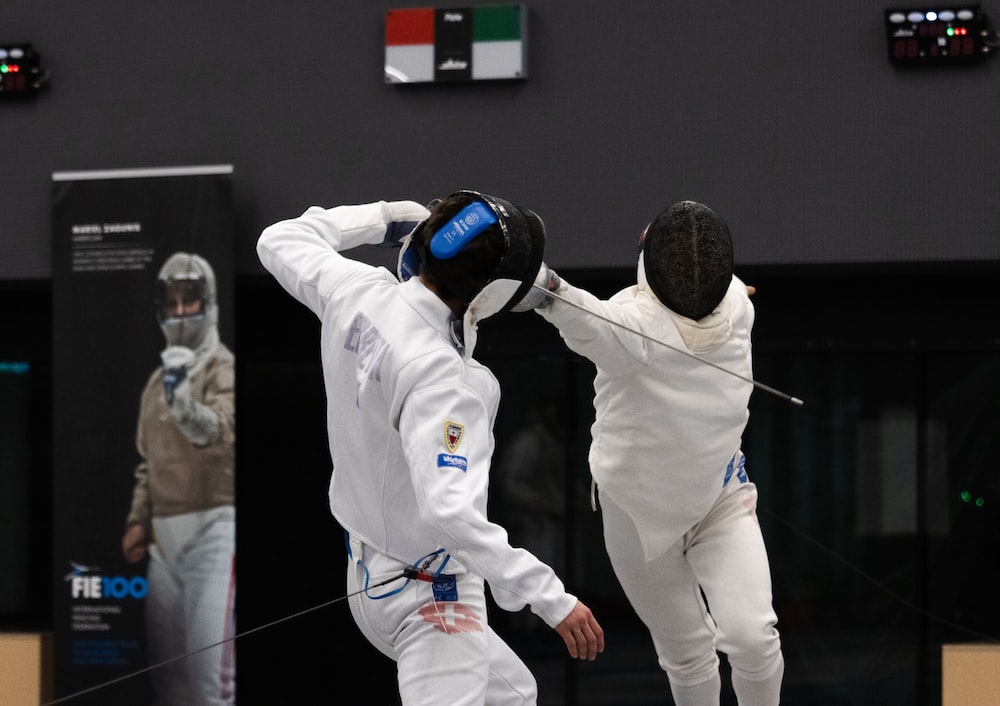 two men in fencing gear in front of a building
