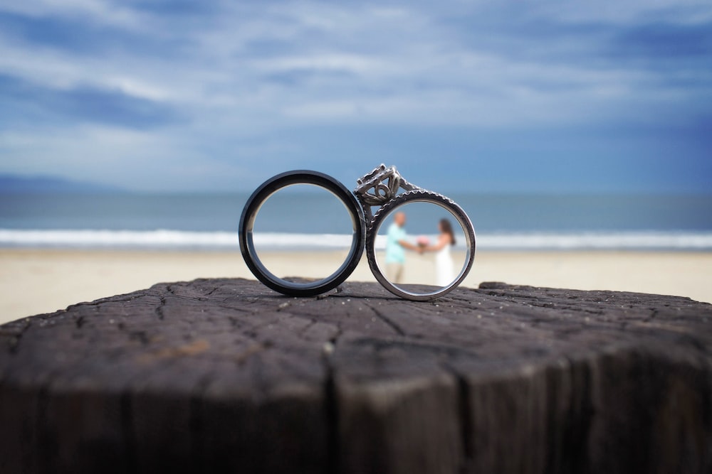 two wedding rings sitting on top of a piece of wood