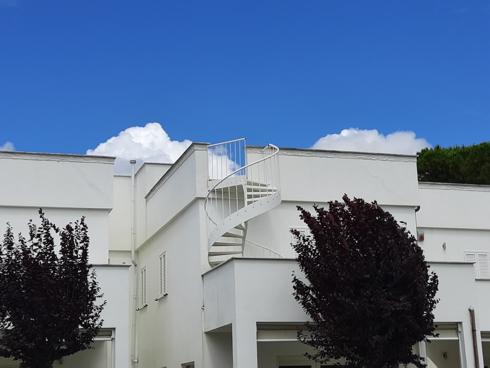 white concrete building near green tree under blue sky during daytime