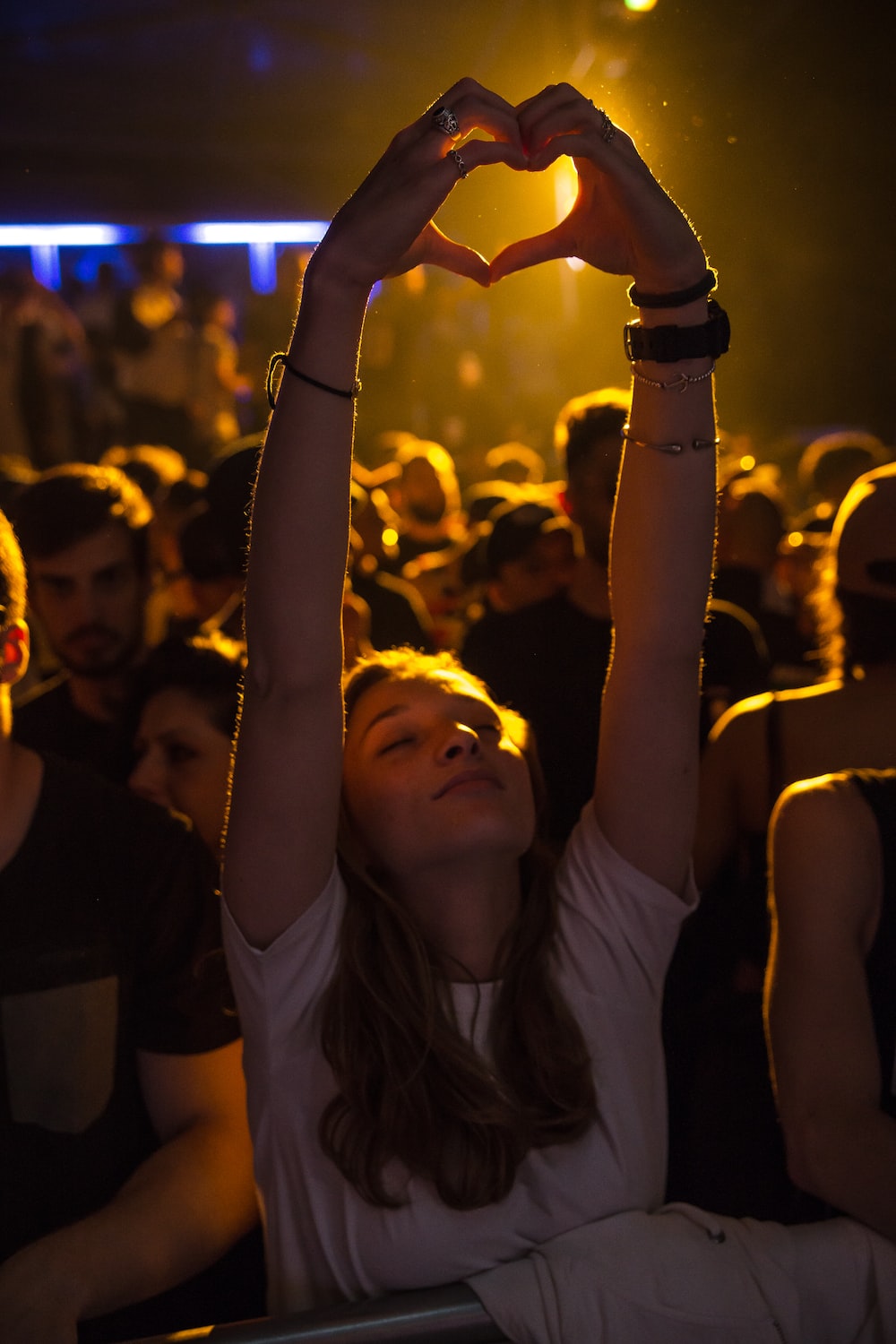 woman at crowd raising her hand while making heart sign