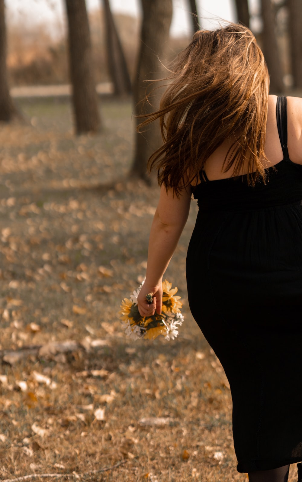 woman in black dress holding brown dried leaves
