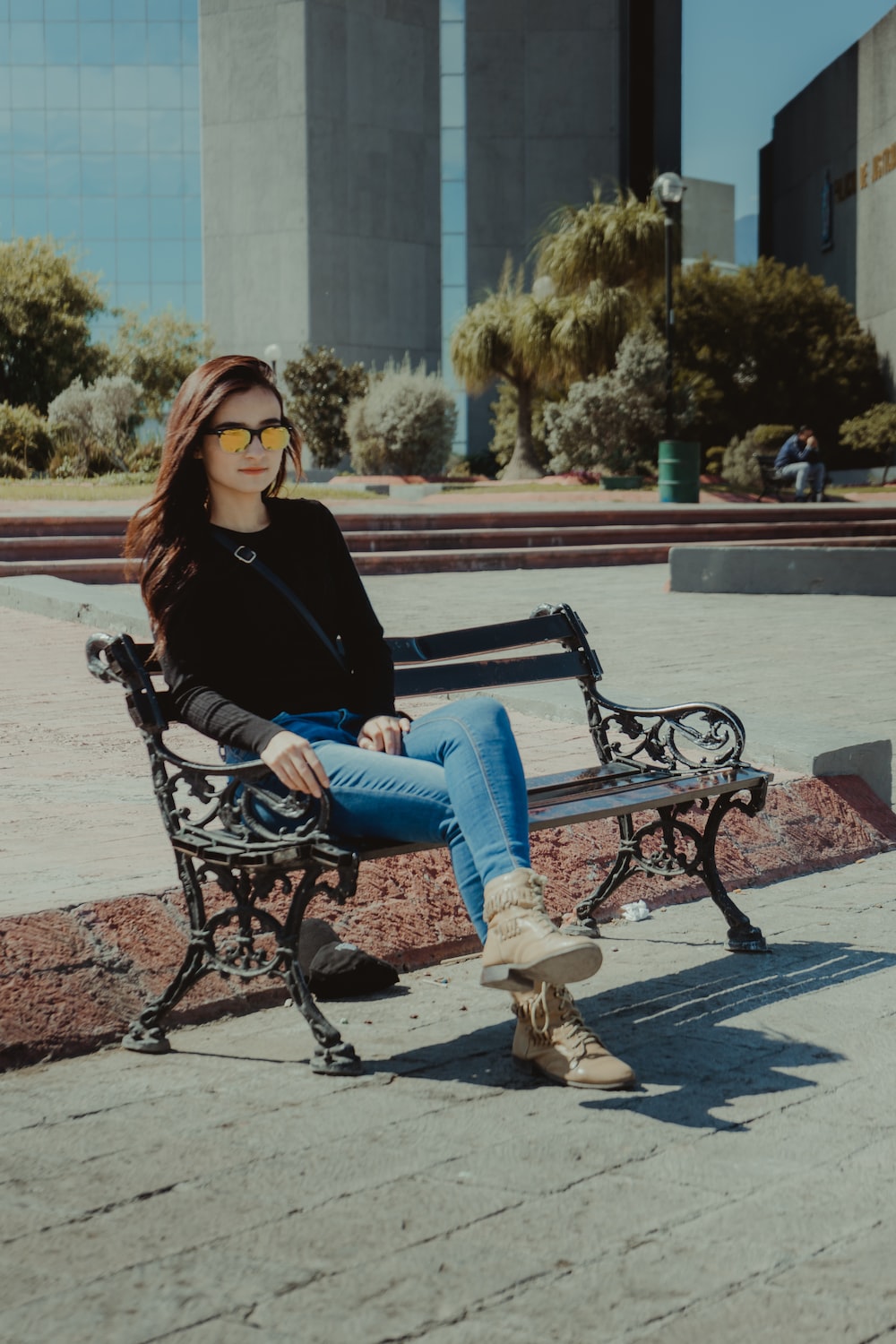 woman in black long sleeve shirt and blue denim jeans sitting on black metal bench during