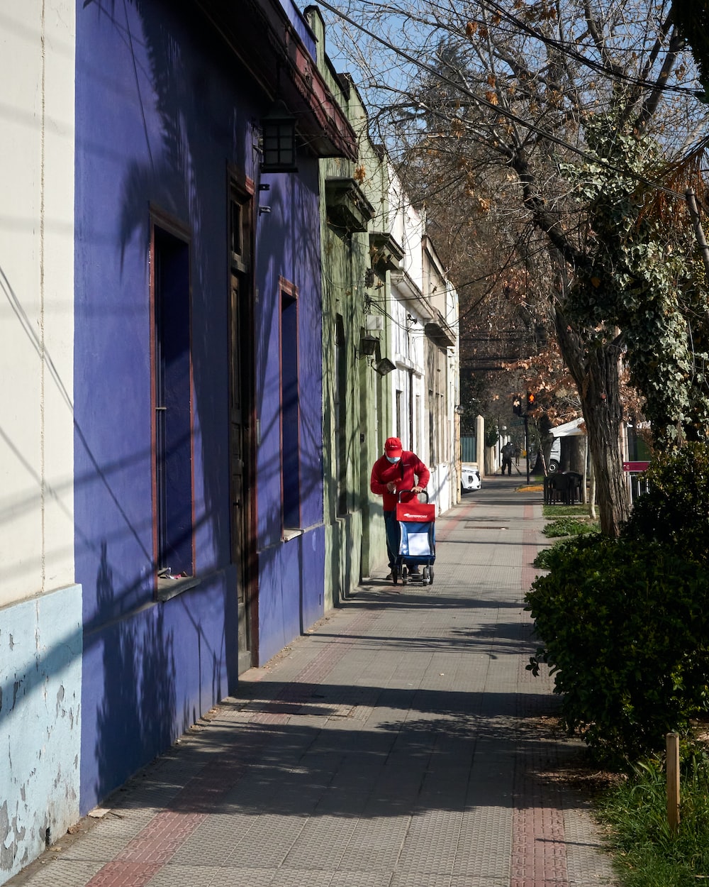 woman in red coat walking on sidewalk during daytime